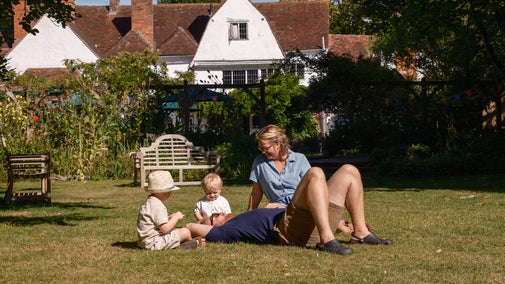A family of four rest on the grass in front of Paycocke's House, Essex